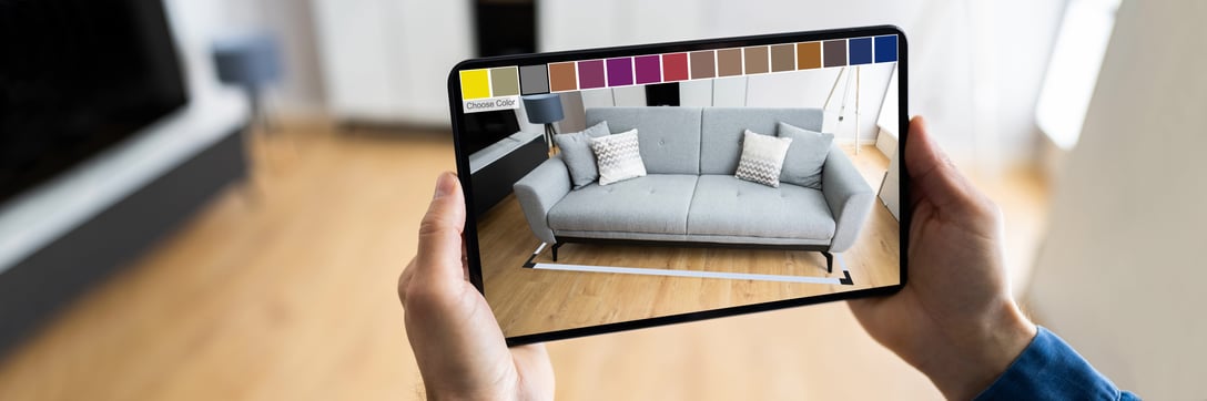 A person using a tablet to view a sofa in a living room using AR.