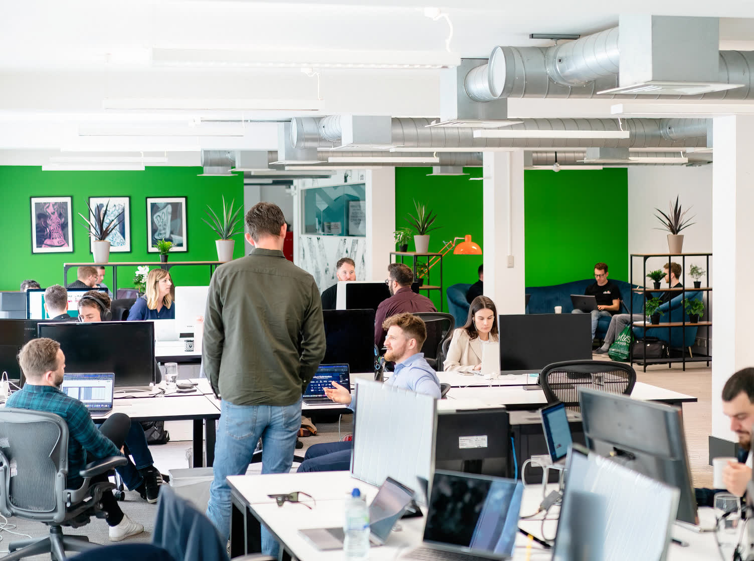 A photo of an open plan office and employees working or talking to each other.